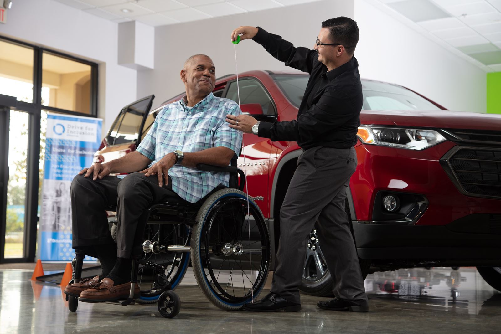 Man seated in manual wheelchair. Another person uses a tape measure to measure his height.