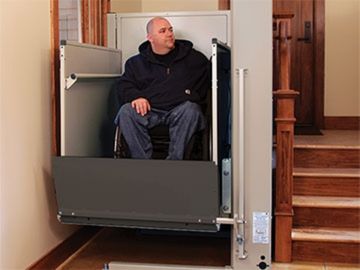 Man usuing a wheelchair on the platform of a residential vertical platform lift