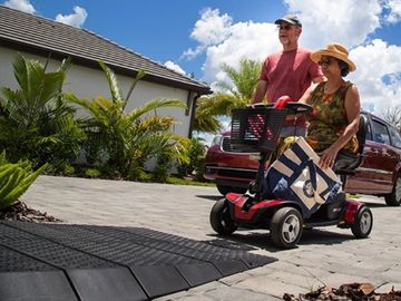 Woman driving mobility scooter approaches rubber threshold ramp