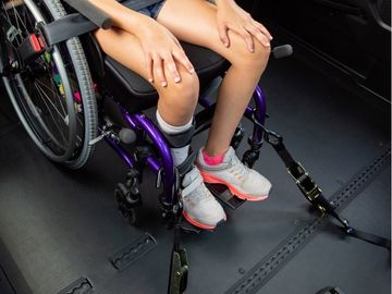 Overhead view of occupied manual wheelchair secured in a vehicle with tie-downs