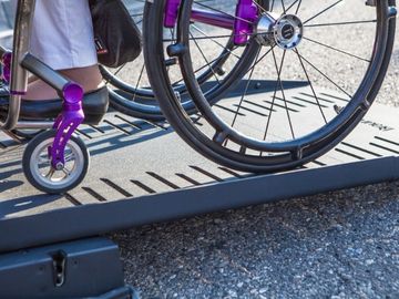 Manual wheelchair user on ramp to enter a BraunAbility Chrysler Pacifica rear-entry wheelchair van; focus on ramp side rails
