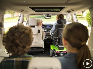 Four people seated in a wheelchair van. The front passenger is seated in a power wheelchair.