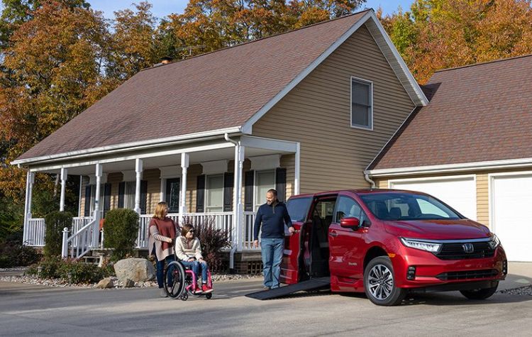 Three people entering a wheelchair accessible vehicle parked in a driveway