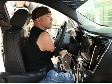 A person with upper extremity limb difference driving a vehicle