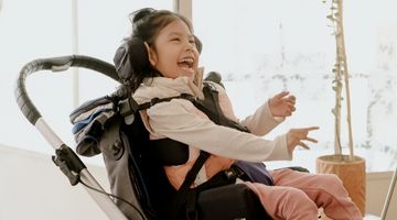 Child smiling while using a manual wheelchair