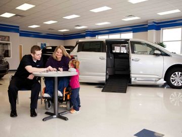Two people reviewing documents at a table in the showroom of a wheelchair accessible van dealership