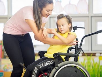 Woman assisting a child in a wheelchair
