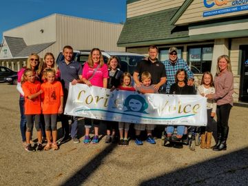 People gathered behind a banner featuring the Lori's Voice logo
