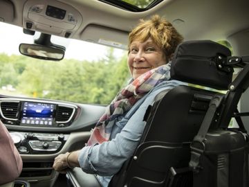 Woman using a power wheelchair in the front-passenger position of a wheelchair accessible van