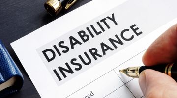 Hand holding pen to complete an application for a disability insurance policy