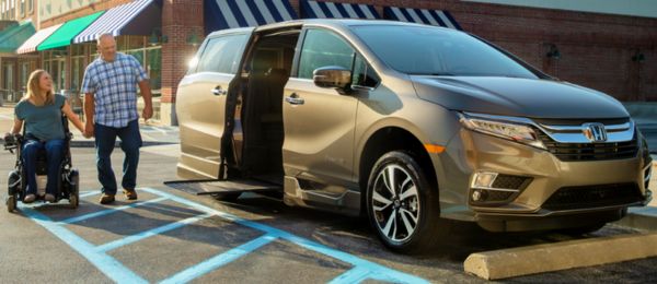 Two people waiting for ramp to deploy from a side-entry wheelchair accessible Honda Odyssey