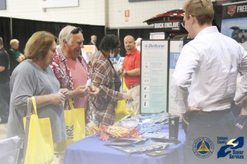 Attendees of a senior expo stand in front of a vendor table