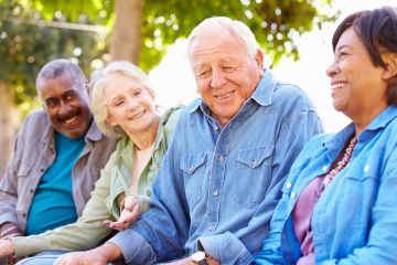 Group of 4 senior citizens seated side-by-side and smiling
