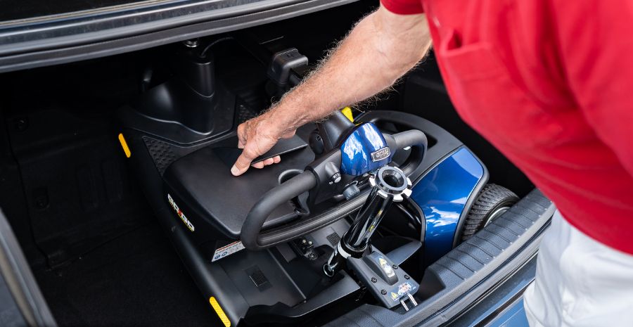 Man loading mobility scooter into trunk of sedan