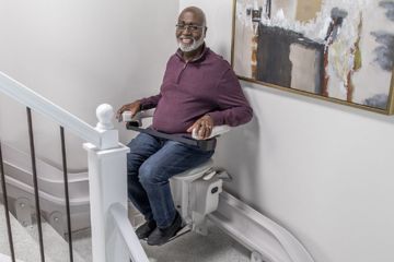 Man using a stair lift in his home, representing professional home access modifications for improved mobility and safety